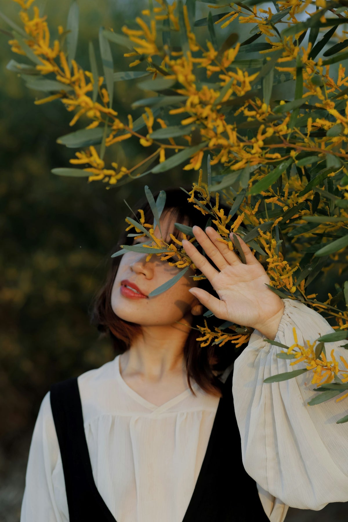 Mujer con blusa crema entre flores doradas, estilo Aurea Moda